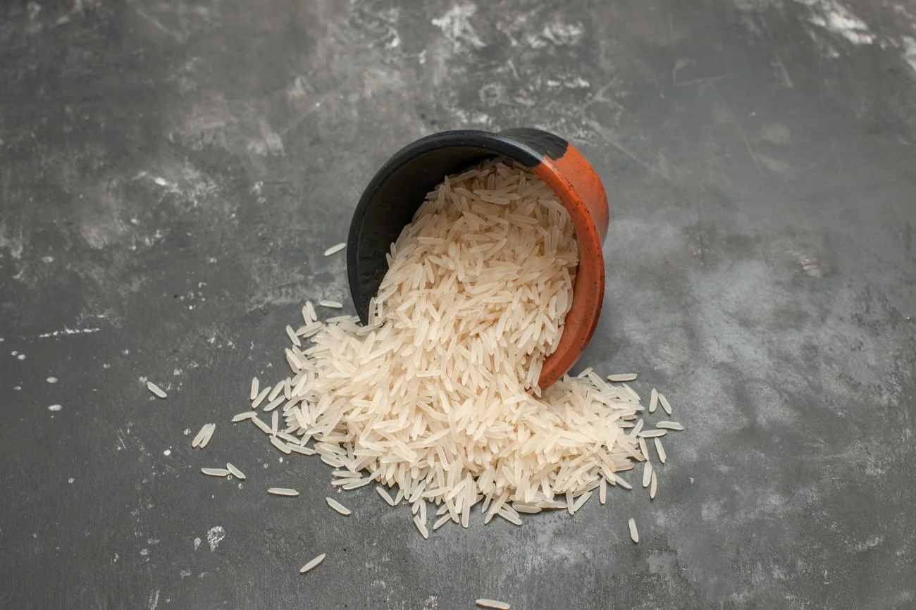 A bowl of cooked long-grain rice on a dark table