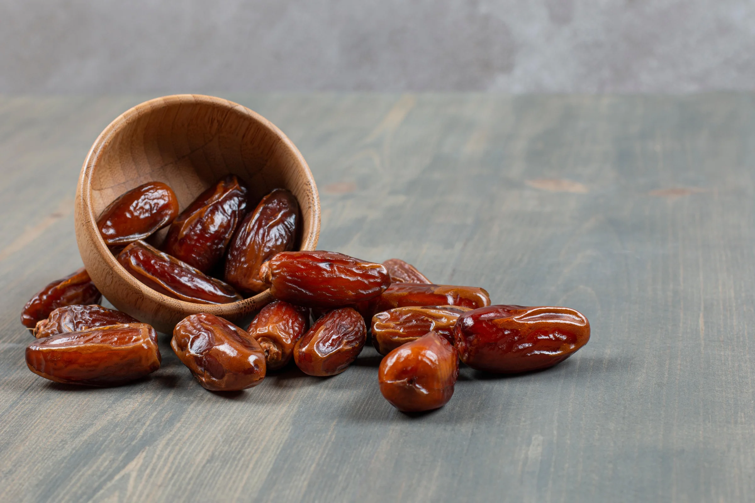 Sweet dates in a wooden bowl on a marble surface
